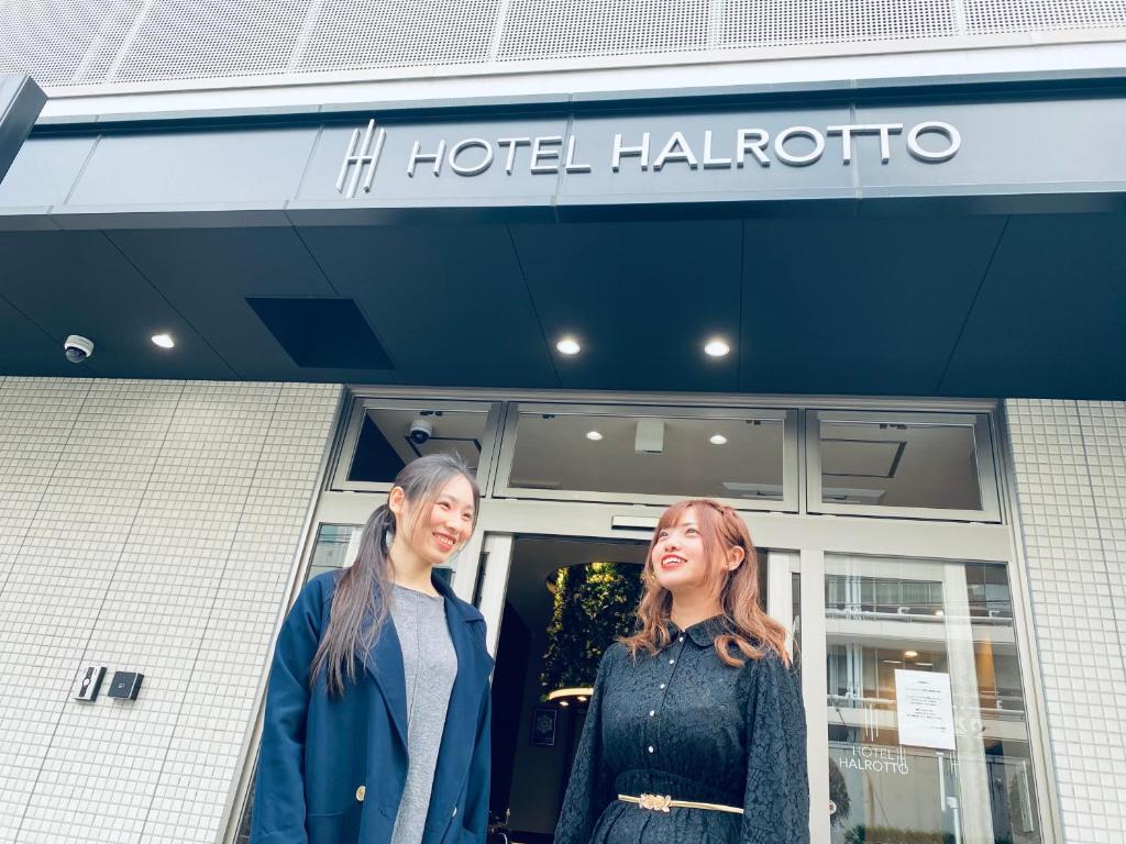 dos mujeres de pie fuera de un hotel haffenore en Hotel Halrotto Fukuoka Hakata en Fukuoka