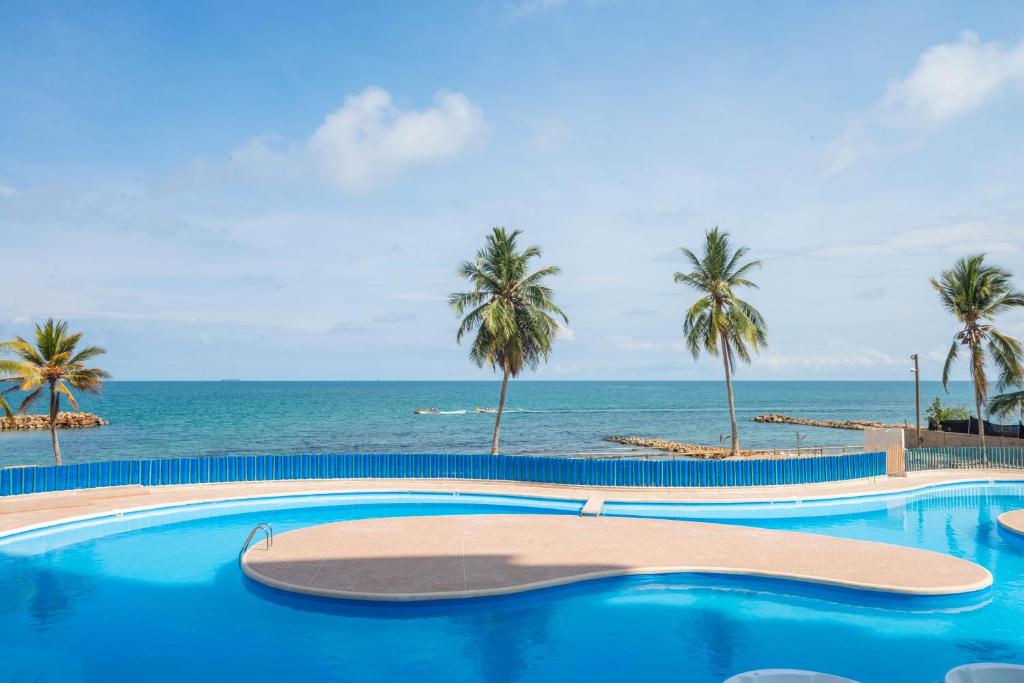 una piscina con palmeras y el océano en Magico Apartamento Frente al Mar 2 Habitaciones PAZ124, en Coveñas