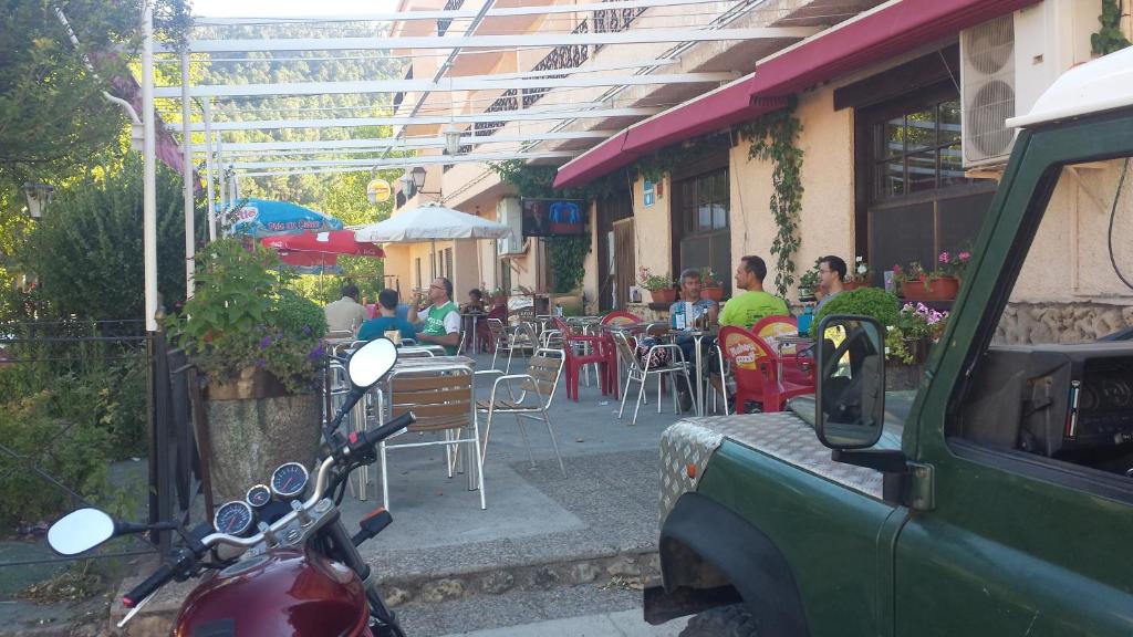 a motorcycle parked in front of a restaurant with people sitting at tables at Hostal Restaurante Los Bronces in Riópar