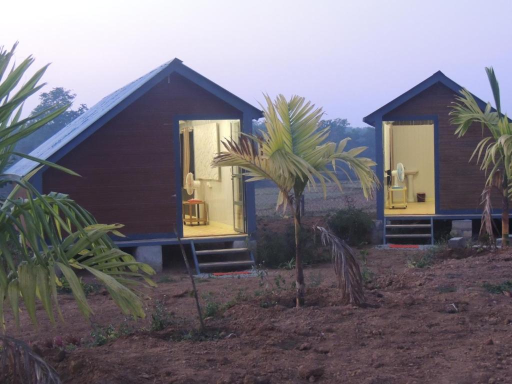 Deux petites maisons avec des palmiers devant elles dans l'établissement Room in Farmhouse - Dandeli - Aura Jungle Stay, à Ganeshgudi