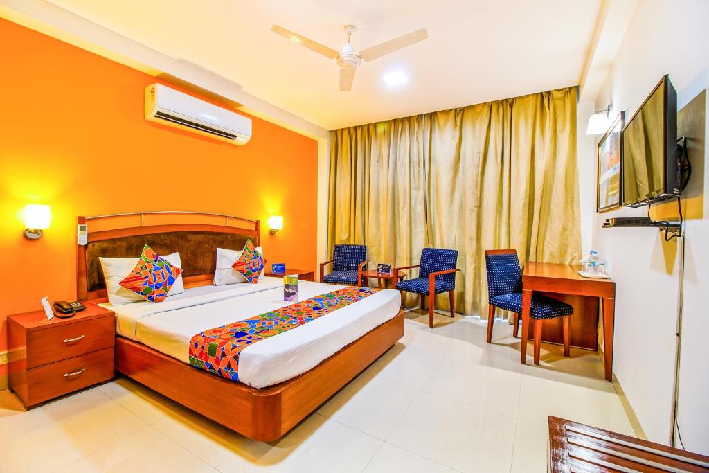 um quarto com uma cama, uma mesa e cadeiras em FabHotel F9 NFC em Nova Deli
