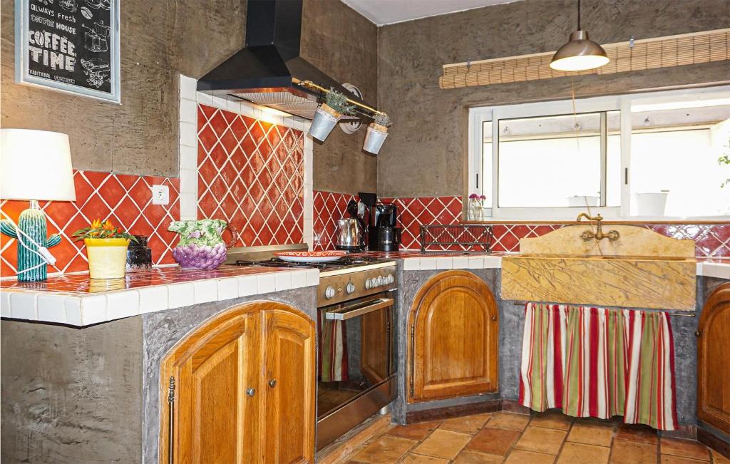 a kitchen with wooden cabinets and a stove top oven at Lovely Home In Roujan With Outdoor Swimming Pool in Roujan