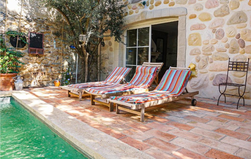 two lounge chairs and a swimming pool next to a house at Lovely Home In Roujan With Outdoor Swimming Pool in Roujan