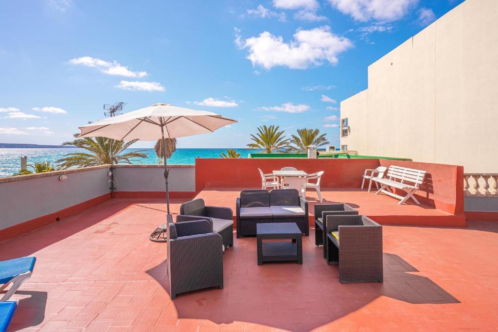 a patio with chairs and an umbrella and the ocean at Ana House in Can Pastilla
