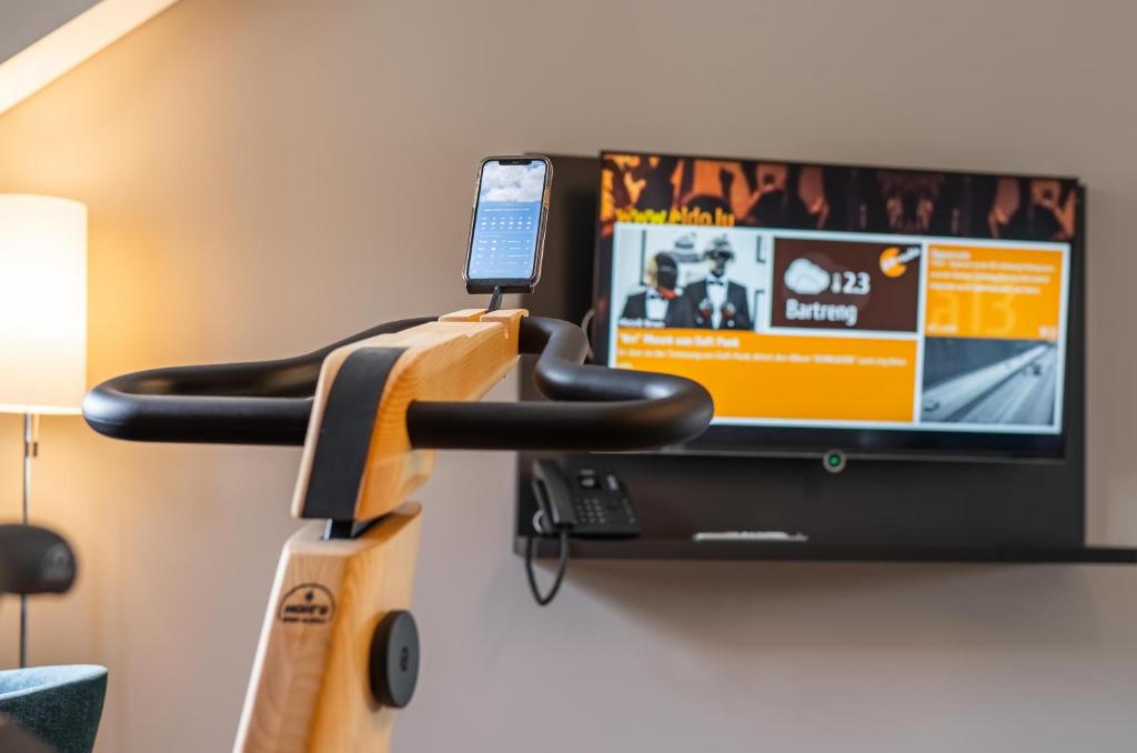 a shelf with a cell phone and a tv on a wall at Hotel Monvillage in Mondercange