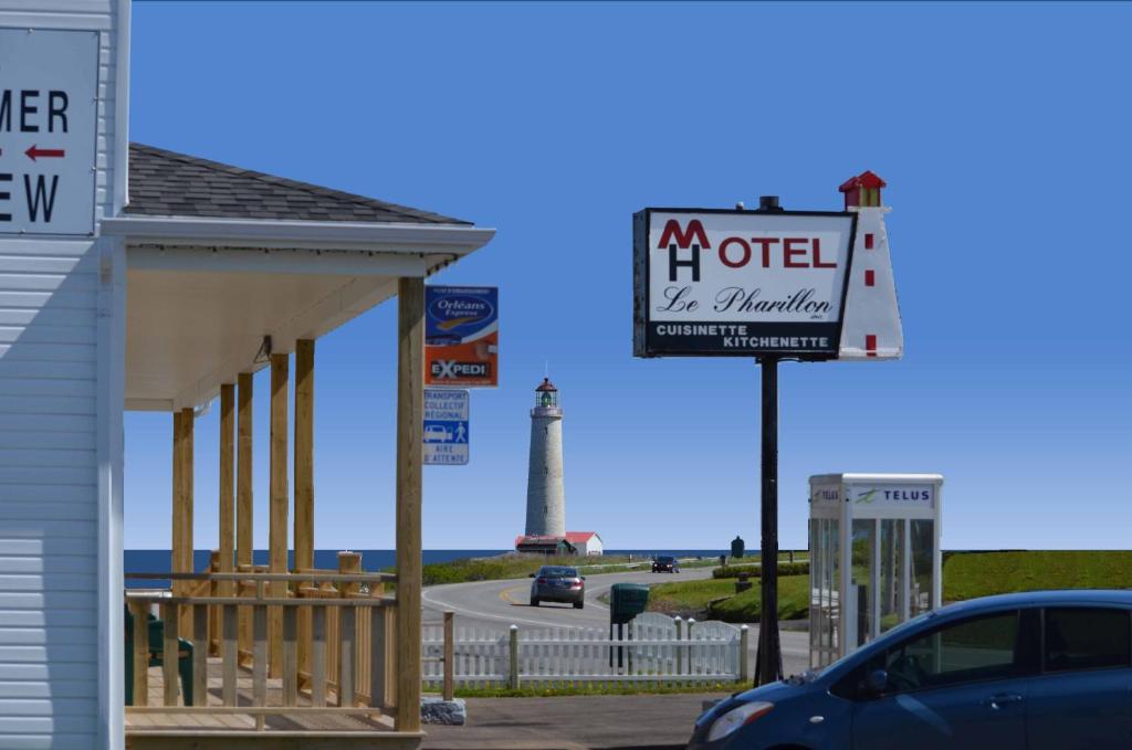 ein Schild vor einem Gebäude mit einem Leuchtturm in der Unterkunft Hôtel-Motel Le Pharillon in Cap-des-Rosiers