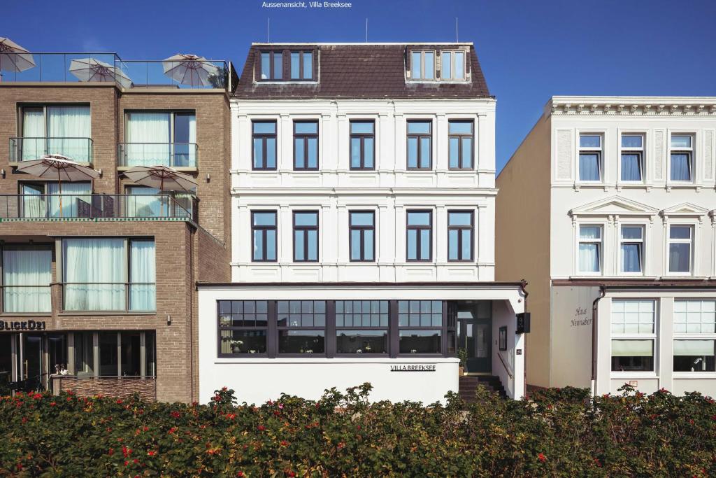 un grand bâtiment blanc devant certains bâtiments dans l'établissement Villa Breeksee, à Norderney