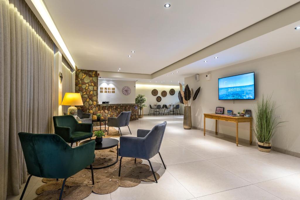 a hospital lobby with chairs and a tv on the wall at Melio Hotel Eilat in Eilat