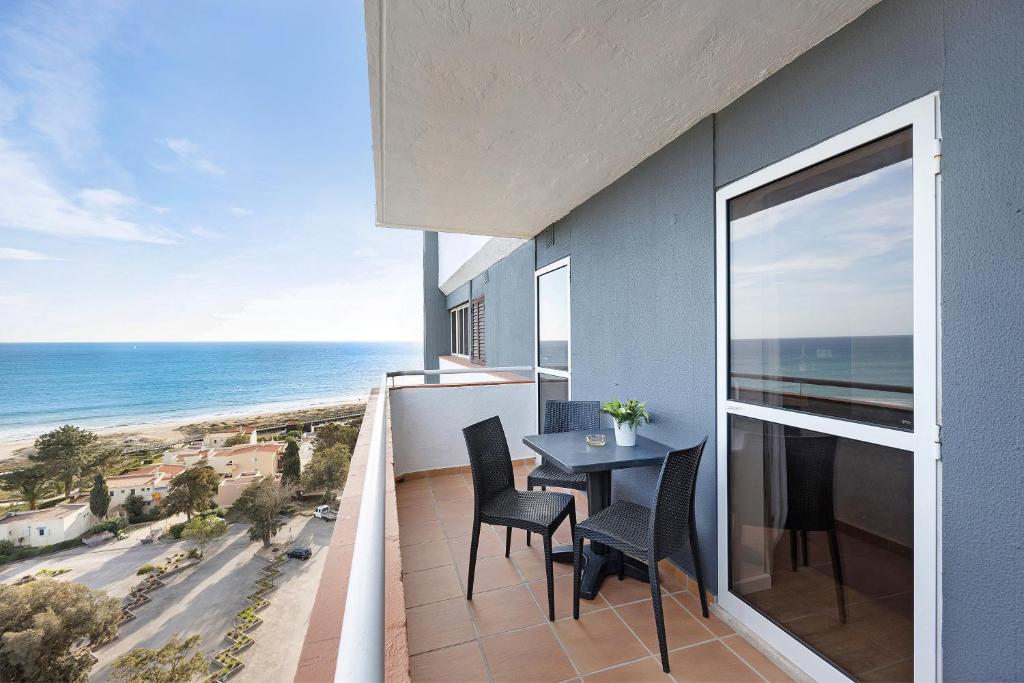 a balcony with a table and chairs and the ocean at Estúdio vista mar Atlântico in Alvor
