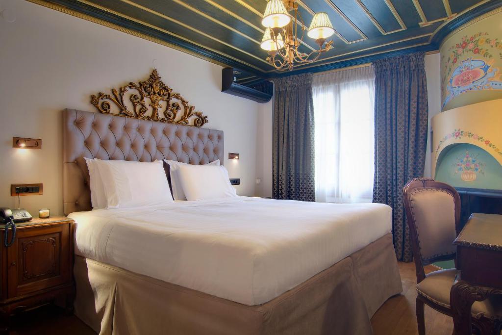 a bedroom with a large bed and a chandelier at ARCHONTARIKI Historic Boutique Hotel in Ioannina
