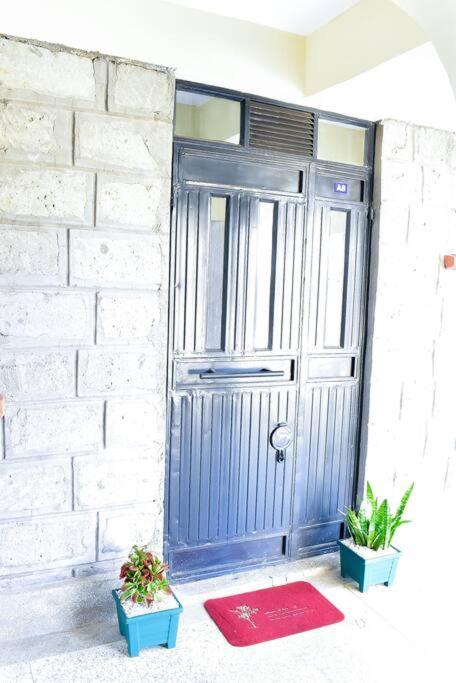 a blue door with two potted plants in front of it at Rorot Spacious one bedroom in Kapsoya with free Wifi in Eldoret