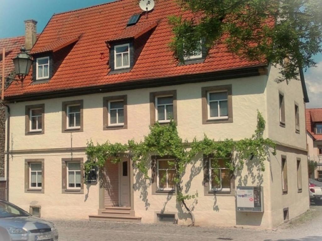 een groot huis met een rood dak op een straat bij Ferienwohnung Haus Gänseplatz in Volkach