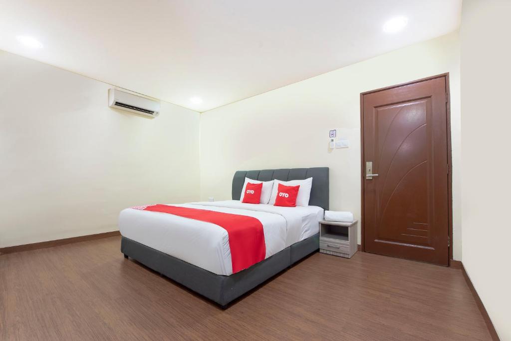 a bedroom with a large bed with red pillows at OYO 90380 Hotel Jasin in Jasin
