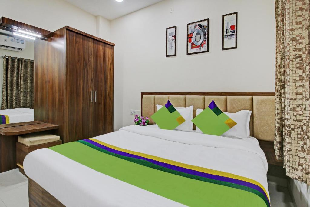 a bedroom with a large bed with a green and yellow blanket at Treebo Trend Krishna Regency ISBT Bus Stop in Bhopal