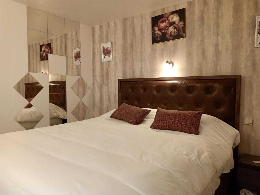 a bedroom with a large white bed with two brown pillows at Astrotel Romorantin-Lanthenay Soirée étape in Romorantin