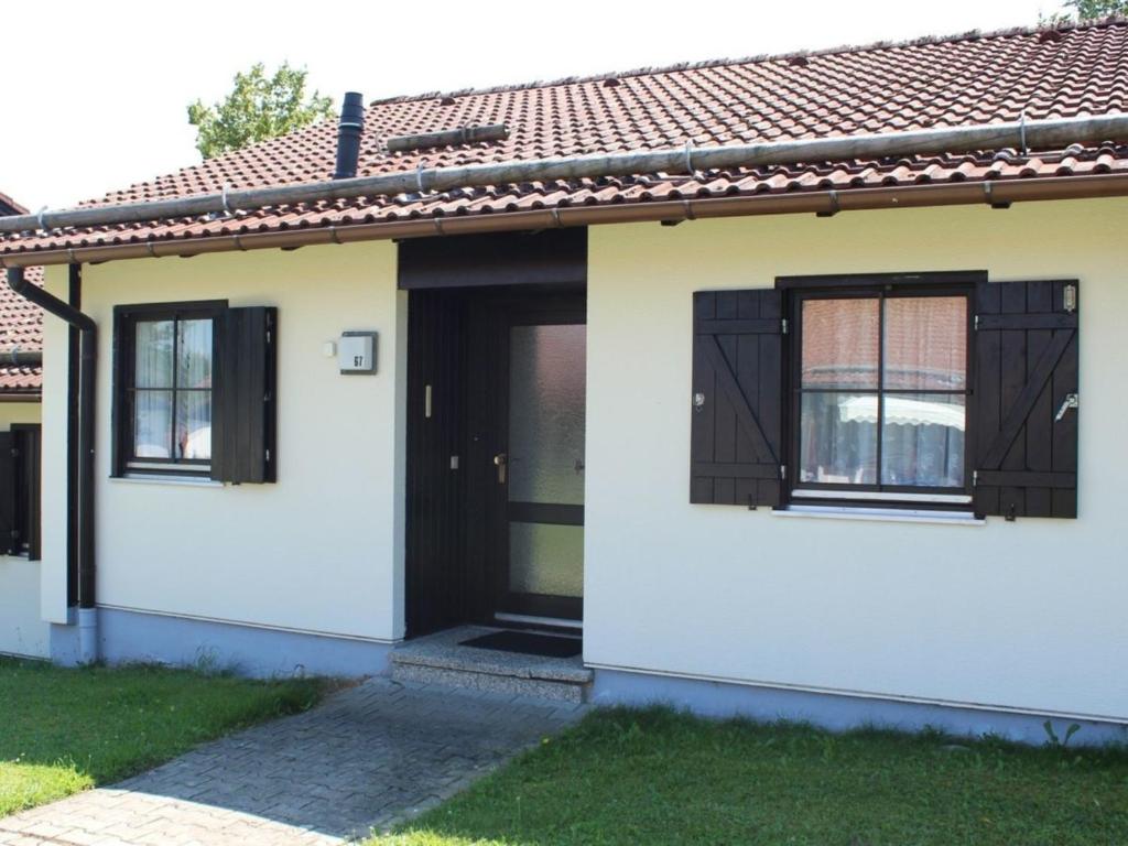 una casa con una puerta negra y ventanas en Ferienhaus Nr 67, Kategorie Komfort, Feriendorf Hochbergle, Allgäu, en Karlsebene