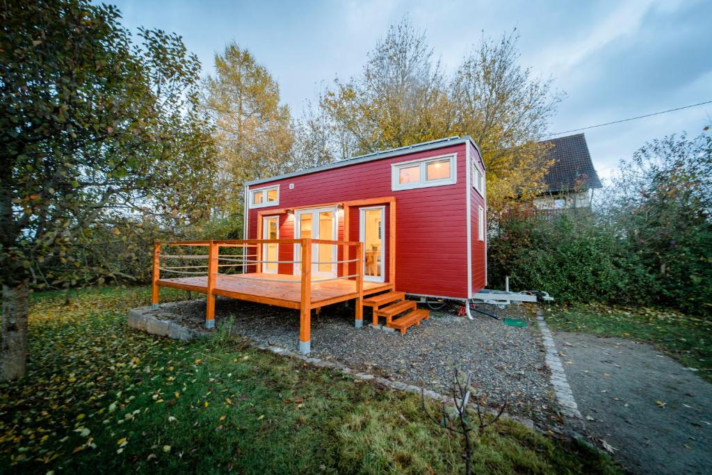 ein rotes winziges Haus mit einer Veranda und einer Terrasse in der Unterkunft Tiny House - Apfel in Wald