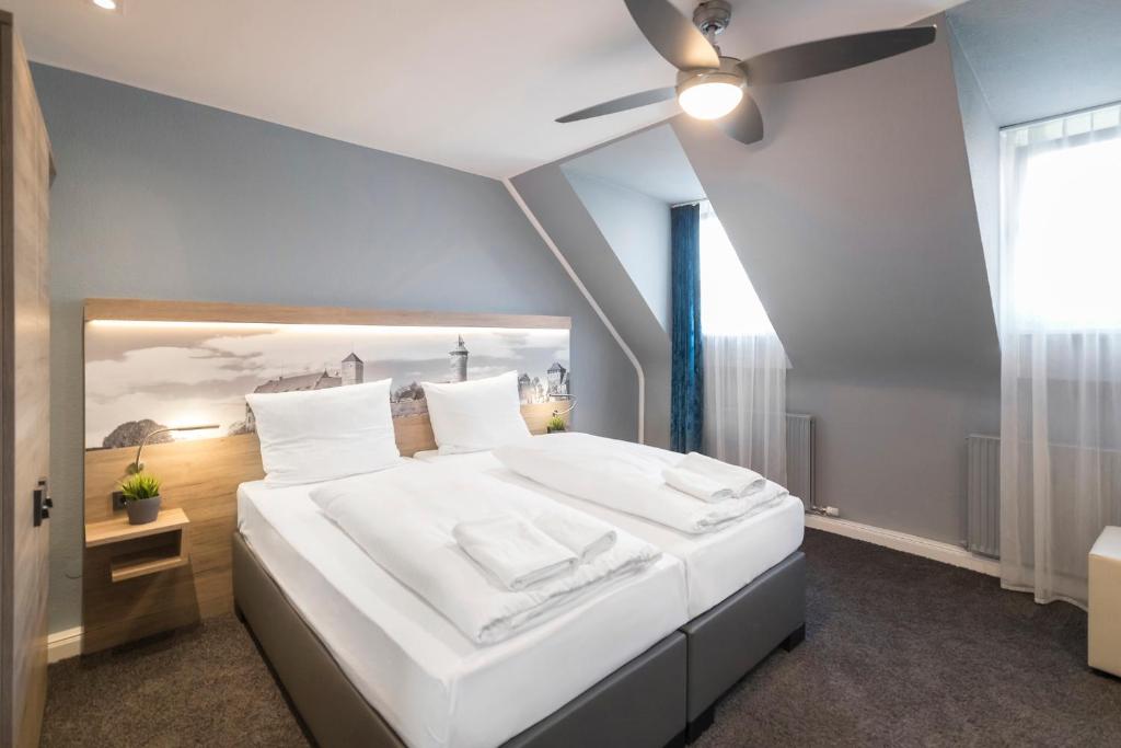 Riverview Apartments by dasPaul في نورنبرغ: غرفة نوم مع سرير أبيض كبير مع مروحة سقف