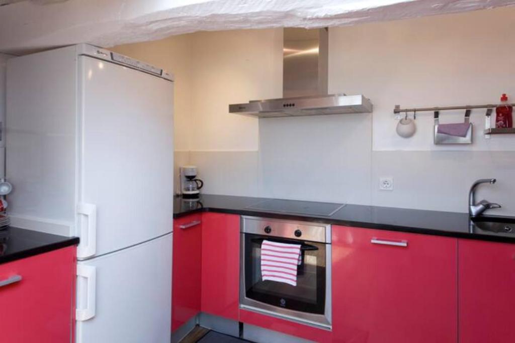 a kitchen with red cabinets and a refrigerator at Pensión Iturriza in Donostia-San Sebastián