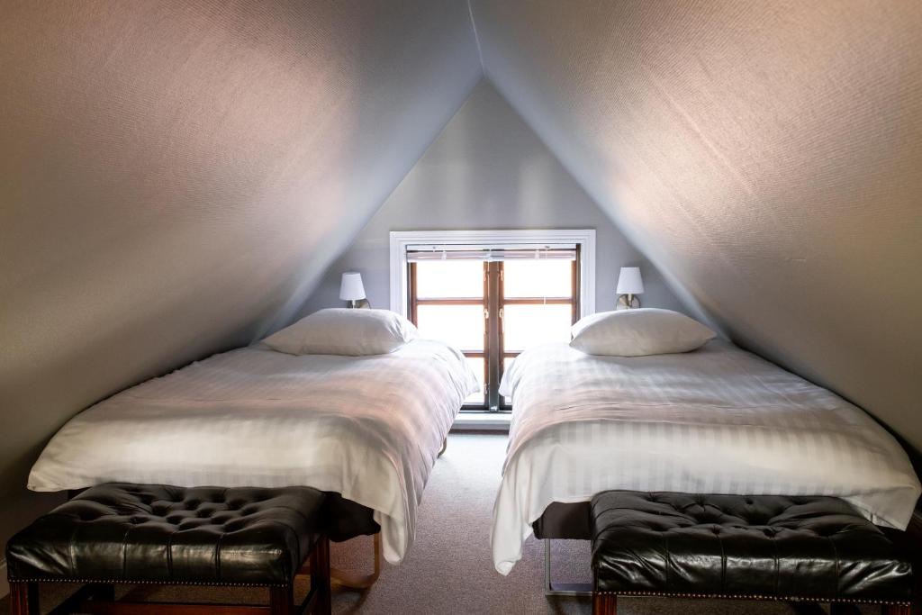 two beds in a attic room with a window at Hotel Hamlet in Helsingør