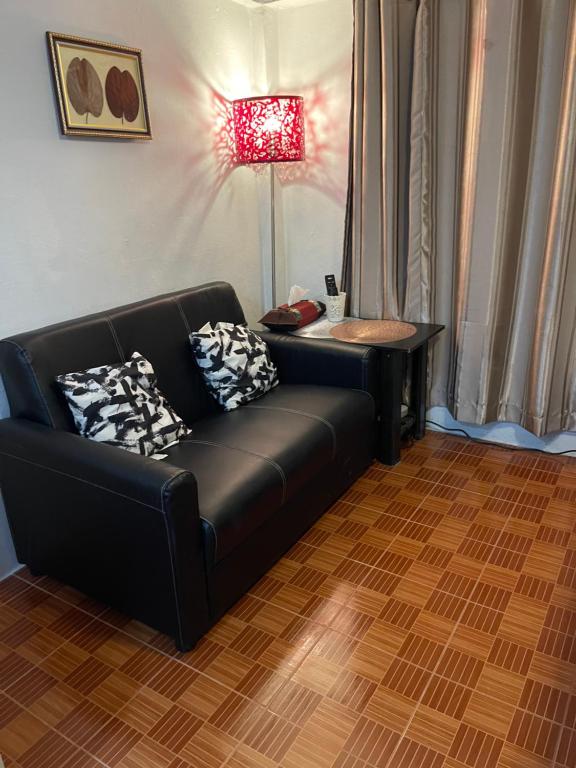 A compact sitting area with a black leather sofa beside a curtained window.