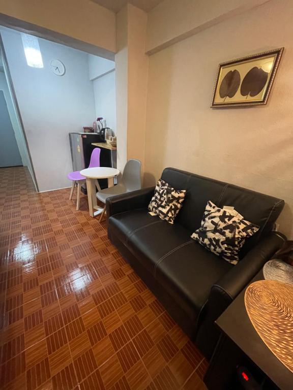 A black sofa faces a small table beside a compact dining and kitchenette area.