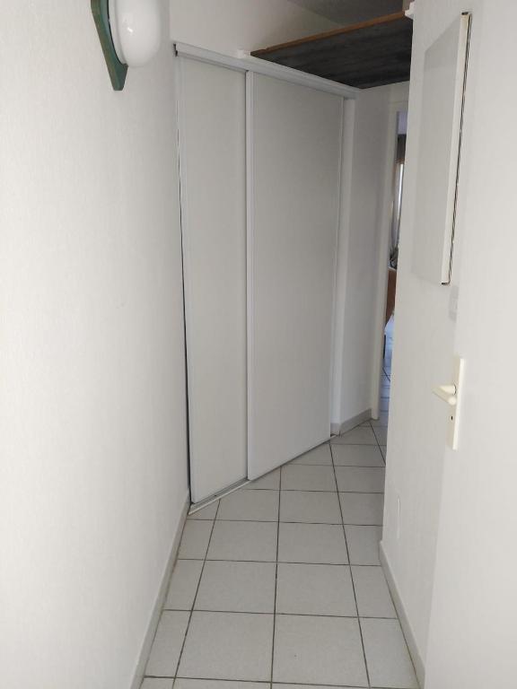 an empty hallway with white walls and white tile floors at Appartement residence le nautile in Le Grau-du-Roi