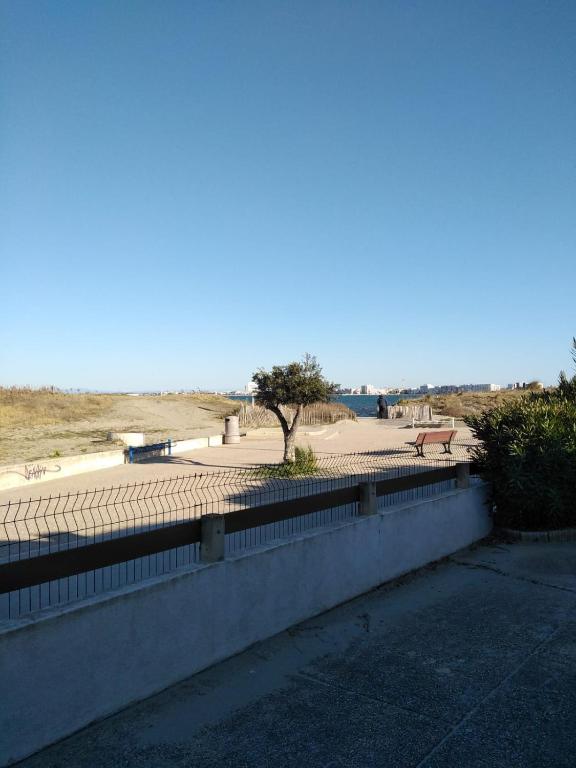 un mur avec un parc avec un arbre et un banc dans l'établissement Appartement residence le nautile, au Grau-du-Roi