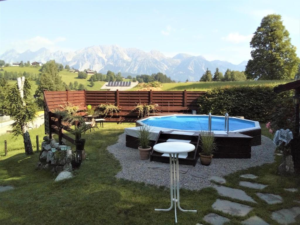 a backyard with a pool and a table and a stool at Landhaus - Neubauer in Schladming