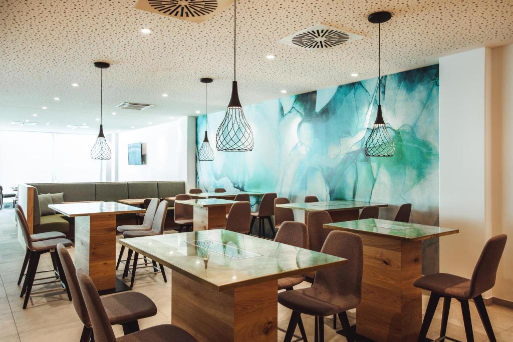 een restaurant met tafels en stoelen en een muurschildering bij Wyndham Garden Munich Messe in München