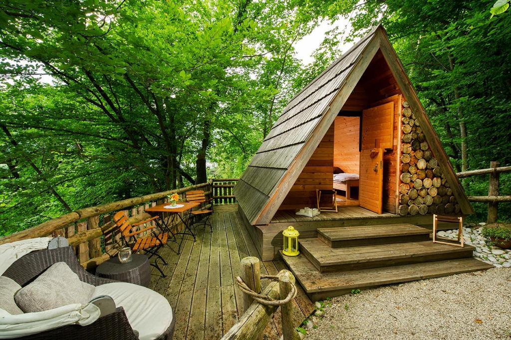 a cabin in the woods with a wooden deck at Glamping Savinja in Ljubno