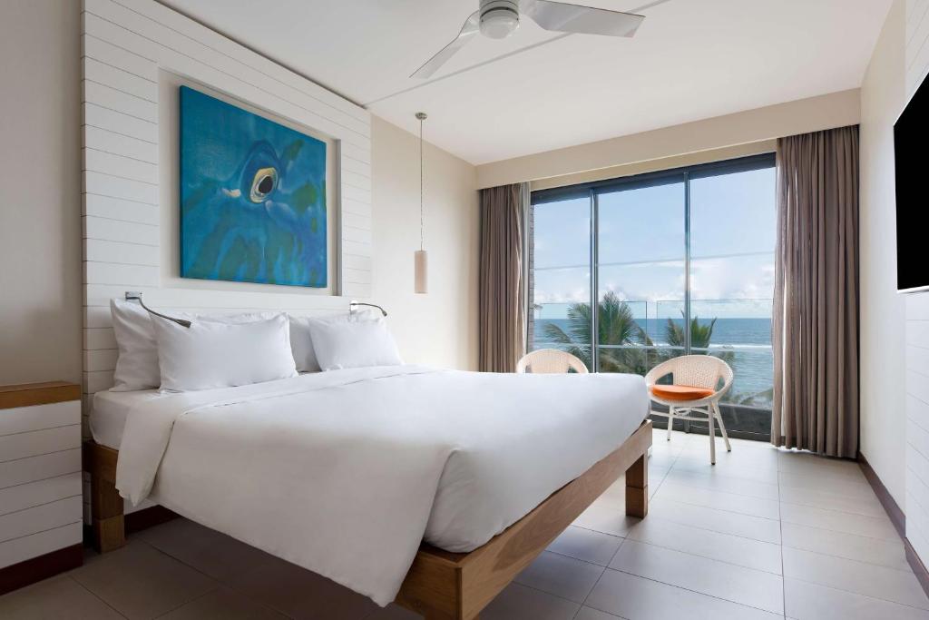 a bedroom with a large white bed and a large window at Radisson Blu Poste Lafayette Resort & Spa (Adults Only) in Poste Lafayette