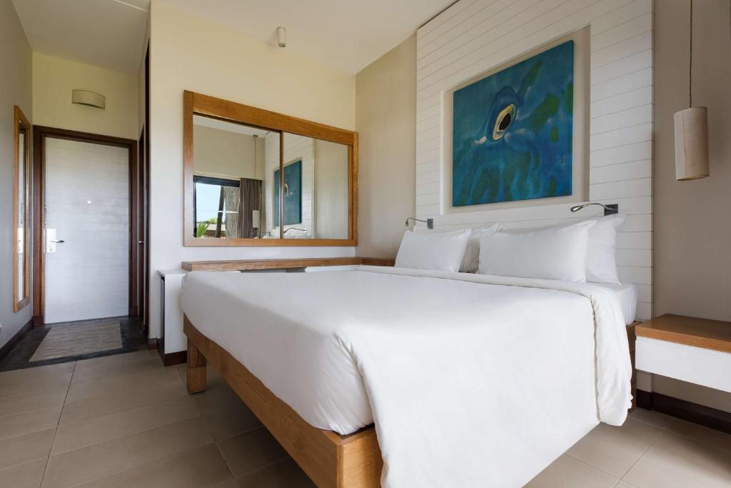a bedroom with a large white bed and a mirror at Radisson Blu Poste Lafayette Resort & Spa (Adults Only) in Poste Lafayette