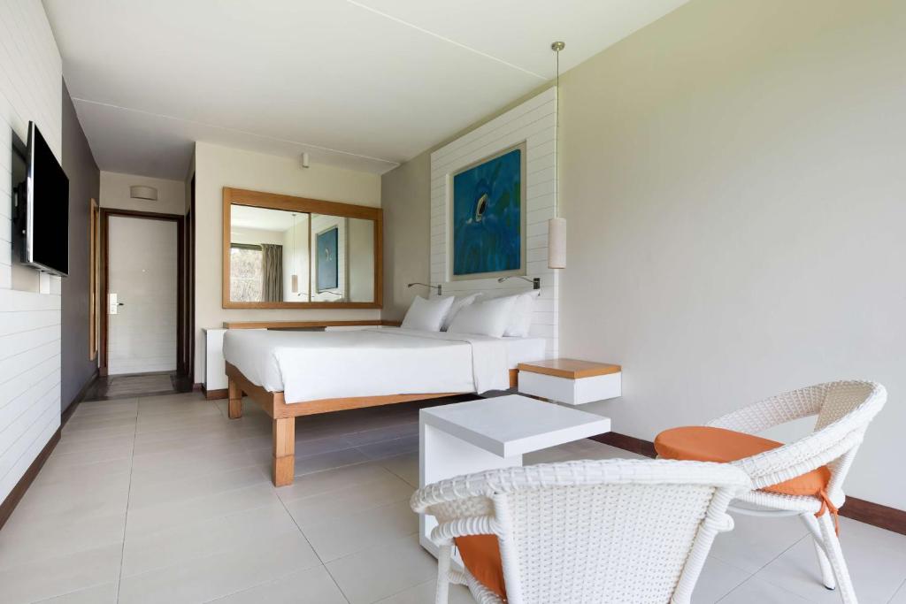 a bedroom with a bed and a table and chairs at Radisson Blu Poste Lafayette Resort & Spa (Adults Only) in Poste Lafayette