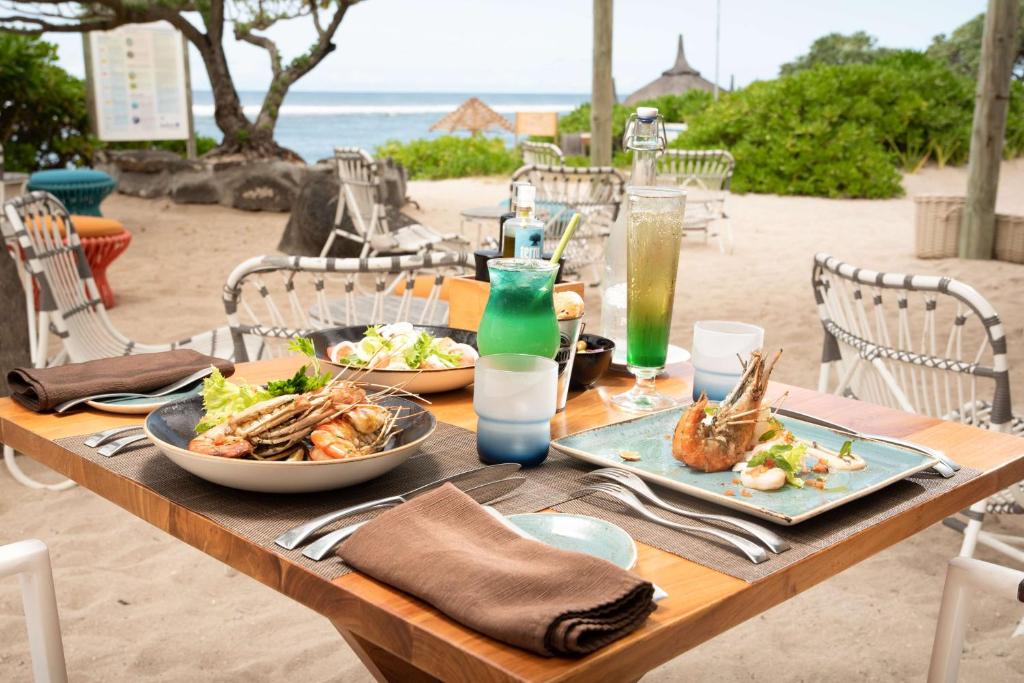 a wooden table with plates of food and drinks on the beach at Radisson Blu Poste Lafayette Resort & Spa (Adults Only) in Poste Lafayette
