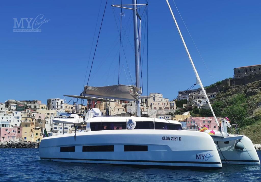 a white boat in the water with buildings in the background at Marina Yacht Charter in Rosignano Solvay