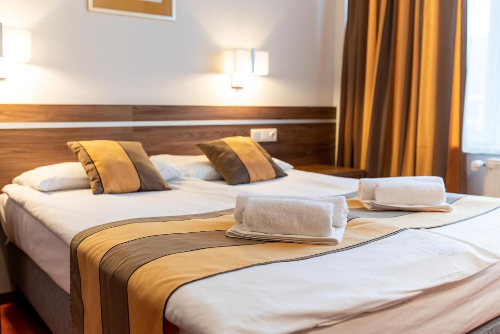 2 Betten in einem Hotelzimmer mit Handtüchern darauf in der Unterkunft Hotel Árpád in Tatabánya