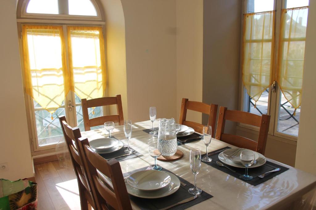 una mesa de comedor con platos y copas de vino en Le 6 Magnifique appt Bagnères-de-Bigorre 3étoiles, en Bagnères-de-Bigorre