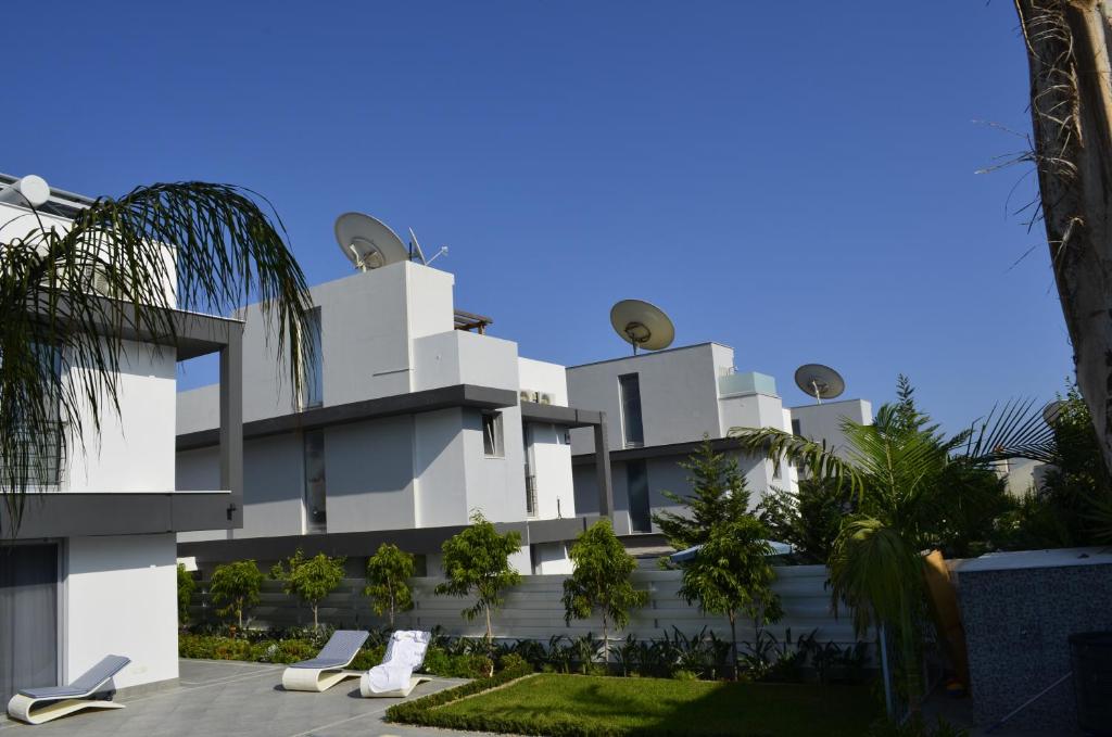 a large white building with chairs in front of it at Fleur De Mer Villa in Hi-Tech Style in Limassol