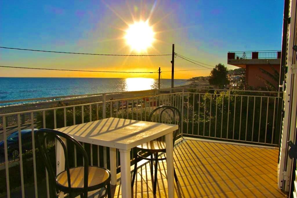 een witte tafel en stoelen op een balkon met uitzicht op de oceaan bij Villa Tripepi in Bova Marina