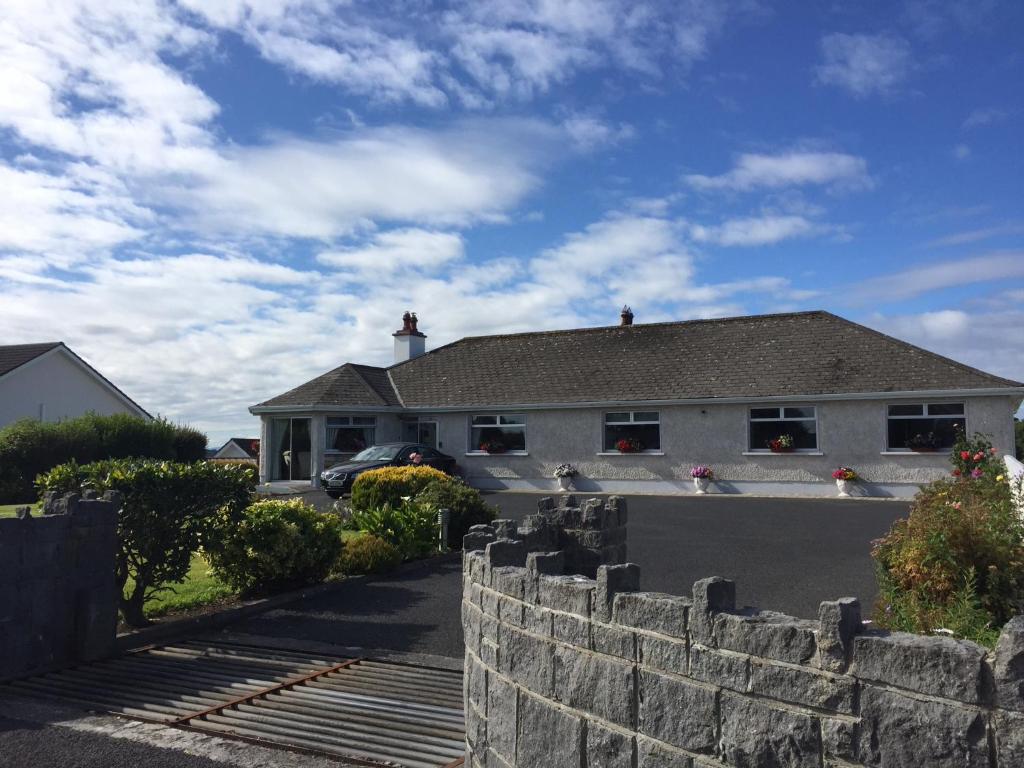 a white house with a stone fence in front of it at Seacrest in Galway