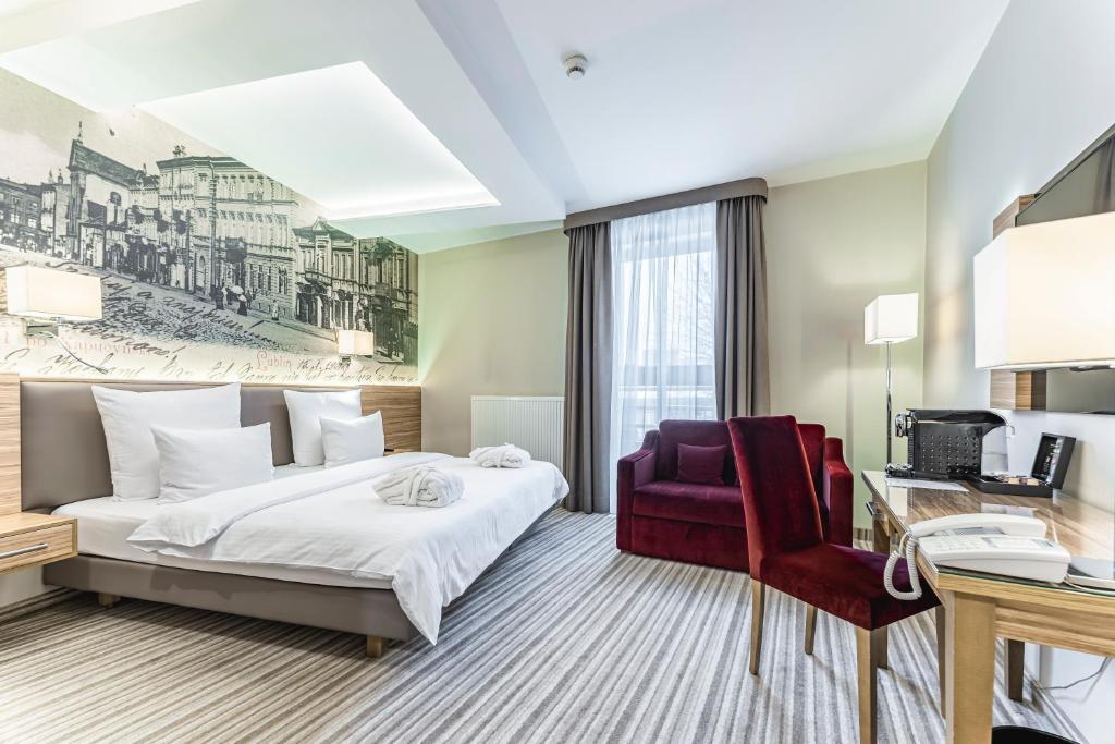 ルブリンにあるホテル ヴィエニャフスキのベッドとデスクが備わるホテルルームです。