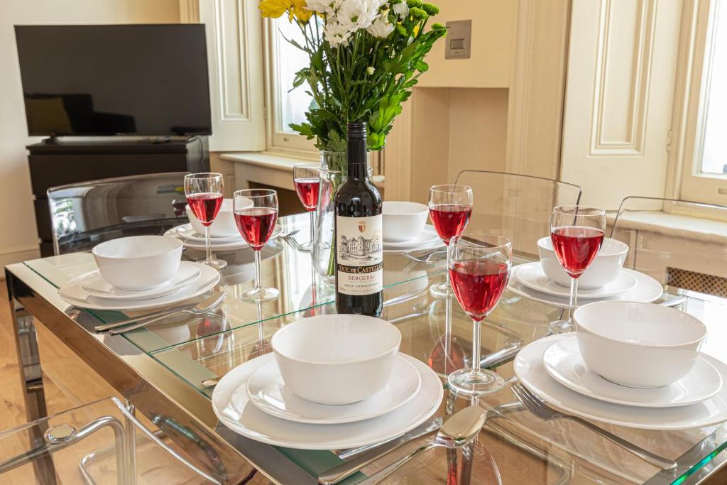 a glass table with a bottle of wine and a vase of flowers at Paddington Gardens in London