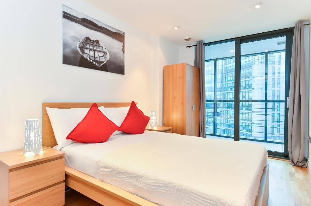 a bedroom with a bed with red pillows at Paddington Gardens in London