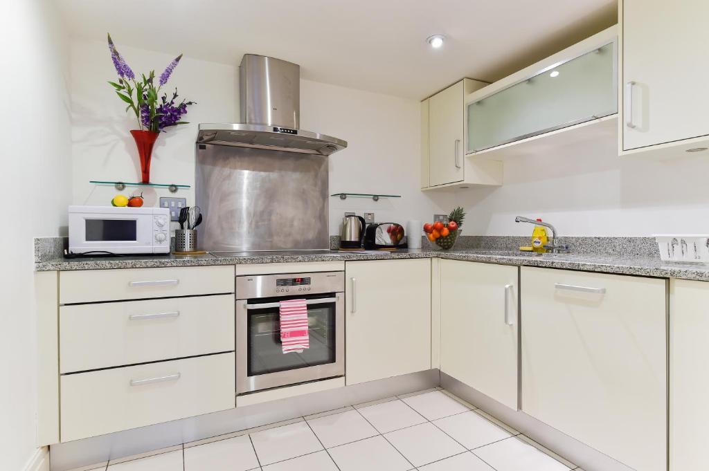 a kitchen with white cabinets and a microwave at Paddington Gardens in London
