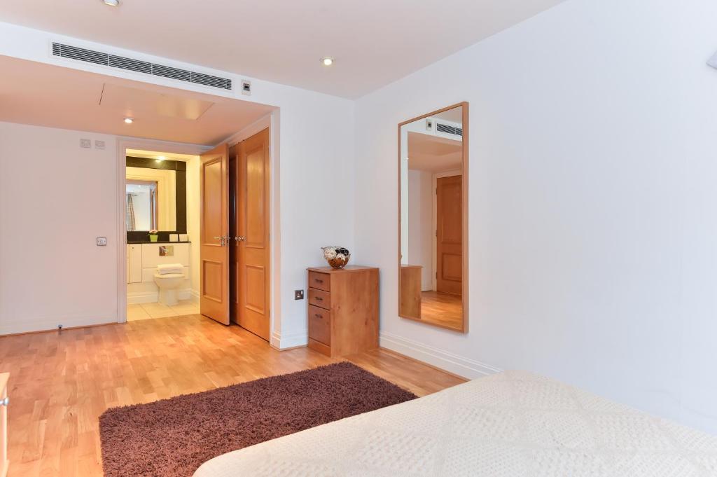 a bedroom with a bed and a mirror and a bathroom at Paddington Gardens in London