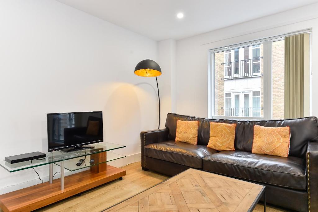 a living room with a leather couch and a television at Paddington Gardens in London