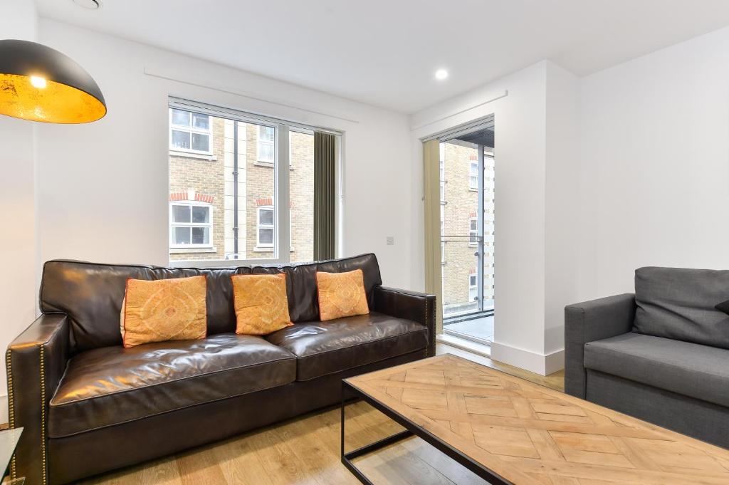 a living room with a leather couch and a chair at Paddington Gardens in London