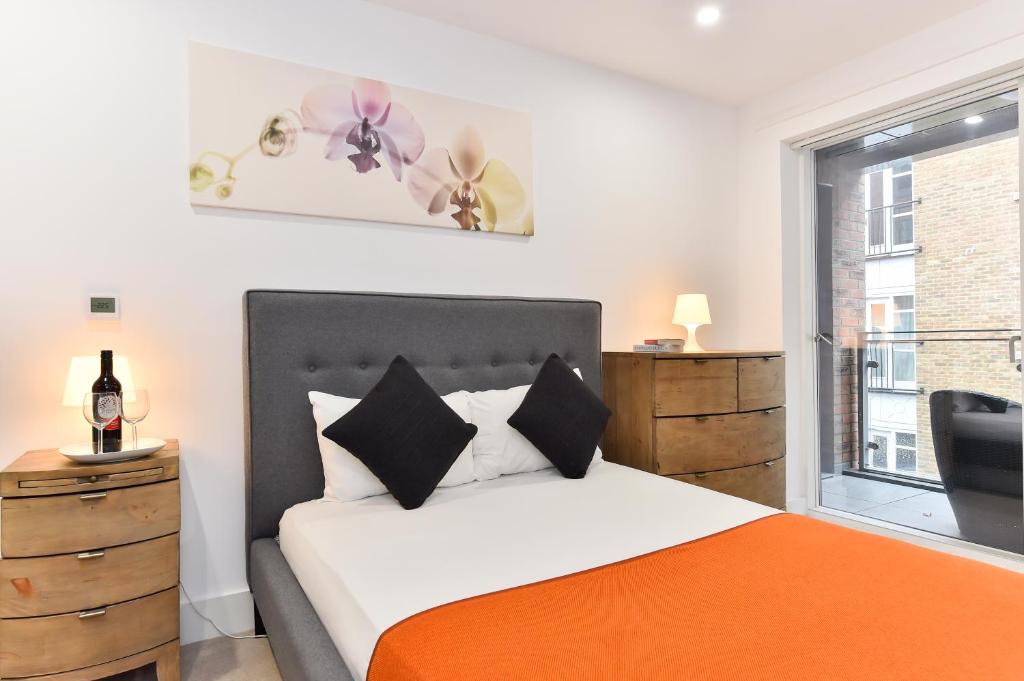 a bedroom with a bed with an orange blanket and a window at Paddington Gardens in London