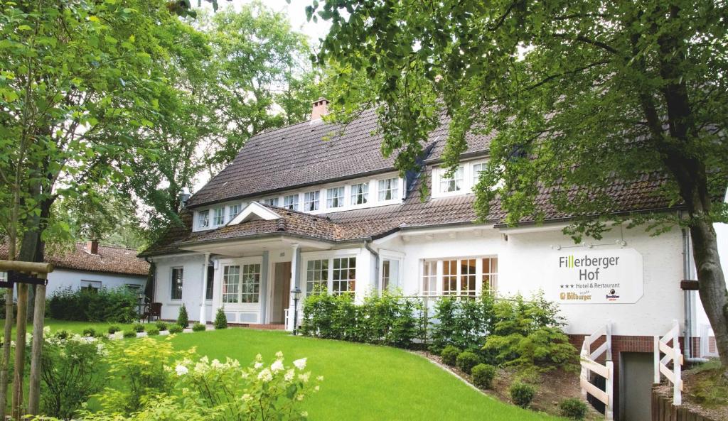 ein weißes Haus mit grünem Rasen davor in der Unterkunft Landhaus Fillerberg in Wildeshausen